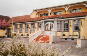 A yellow country inn with red roof tiles and white stairs in Vitis.