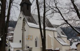 A church in winter with snow-covered ground and bare trees.