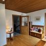 Wood-paneled room with bench, table lamp and open access to a bathroom.