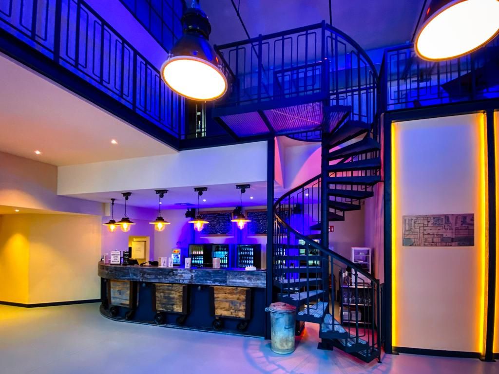 Interior view of a bar with spiral staircase and blue lighting.
