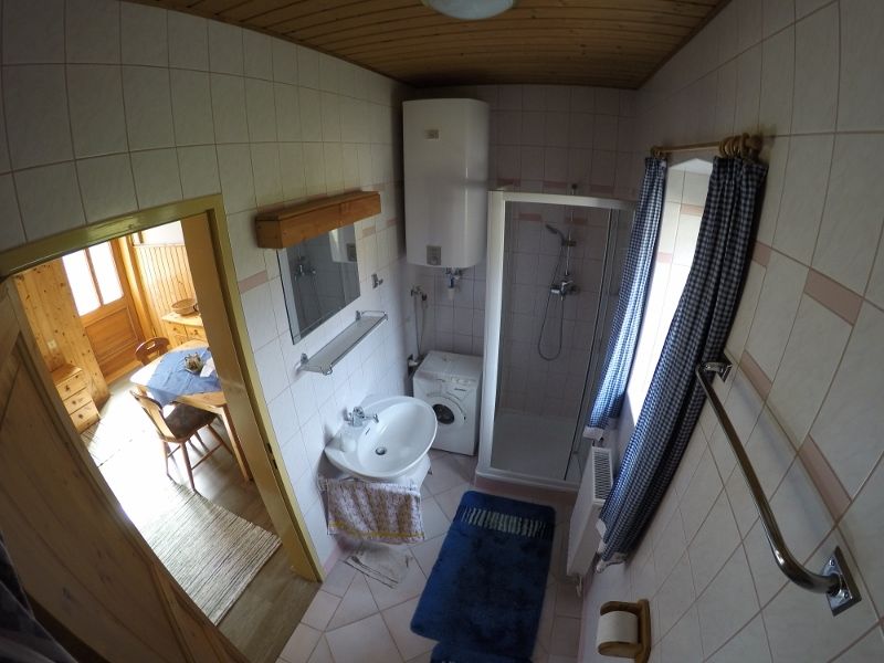 Bathroom with shower, washbasin, washing machine and blue curtains.