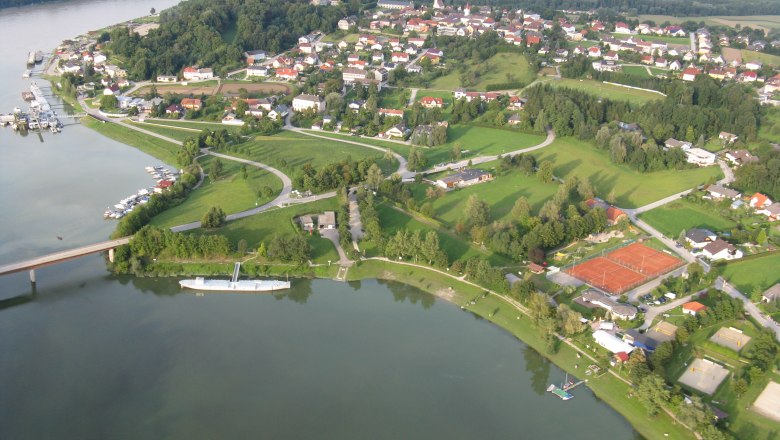 Aerial view of a water sports center with tennis courts, boat docks and a river.