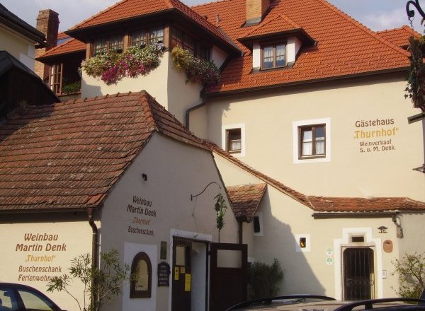 Exterior view of a traditional building with red tiled roofs and flower boxes on the windows.