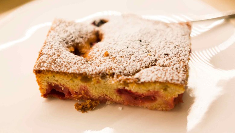 A slice of homemade cake dusted with powdered sugar on a plate.