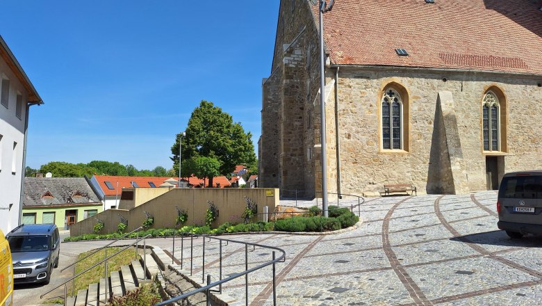 Stone staircase leads to a historic building with a red tiled roof and Gothic windows.