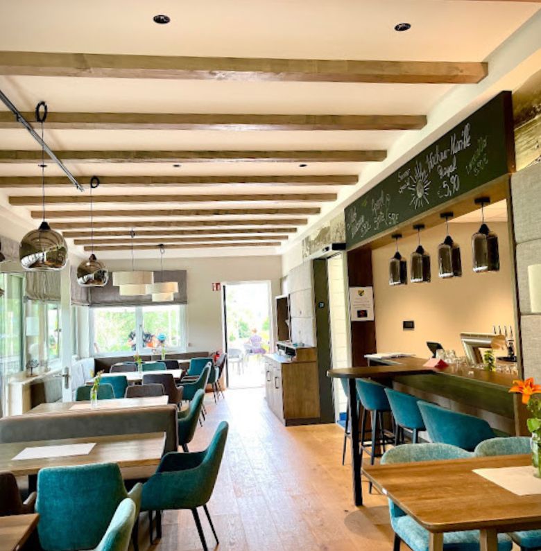 Restaurant area inside with tables and green armchairs
