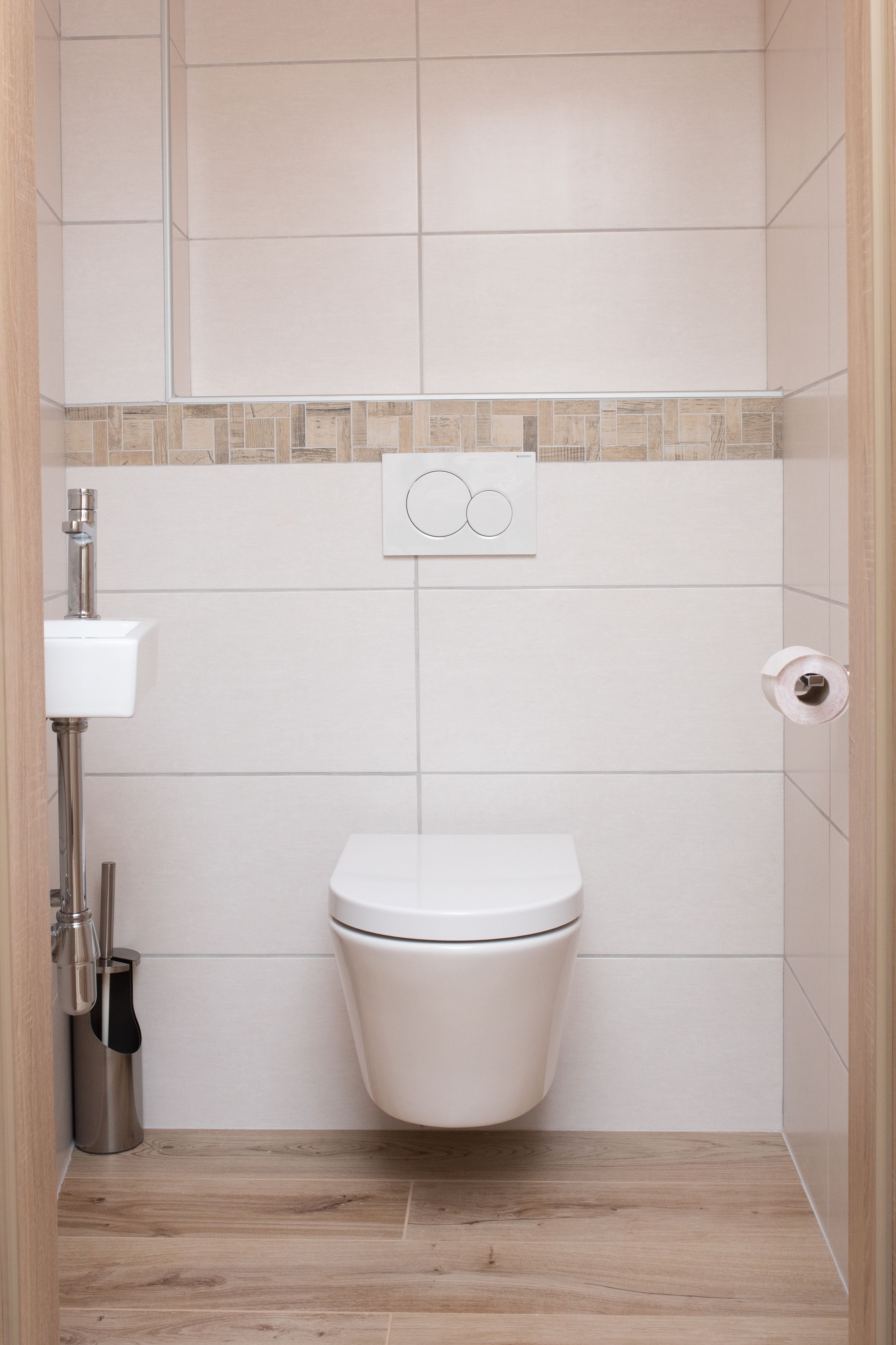 Modern bathroom with hanging toilet, small washbasin and toilet roll holder.