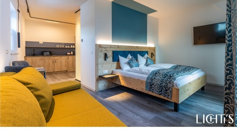 Modern apartment with wooden bed, yellow sofa and kitchenette.