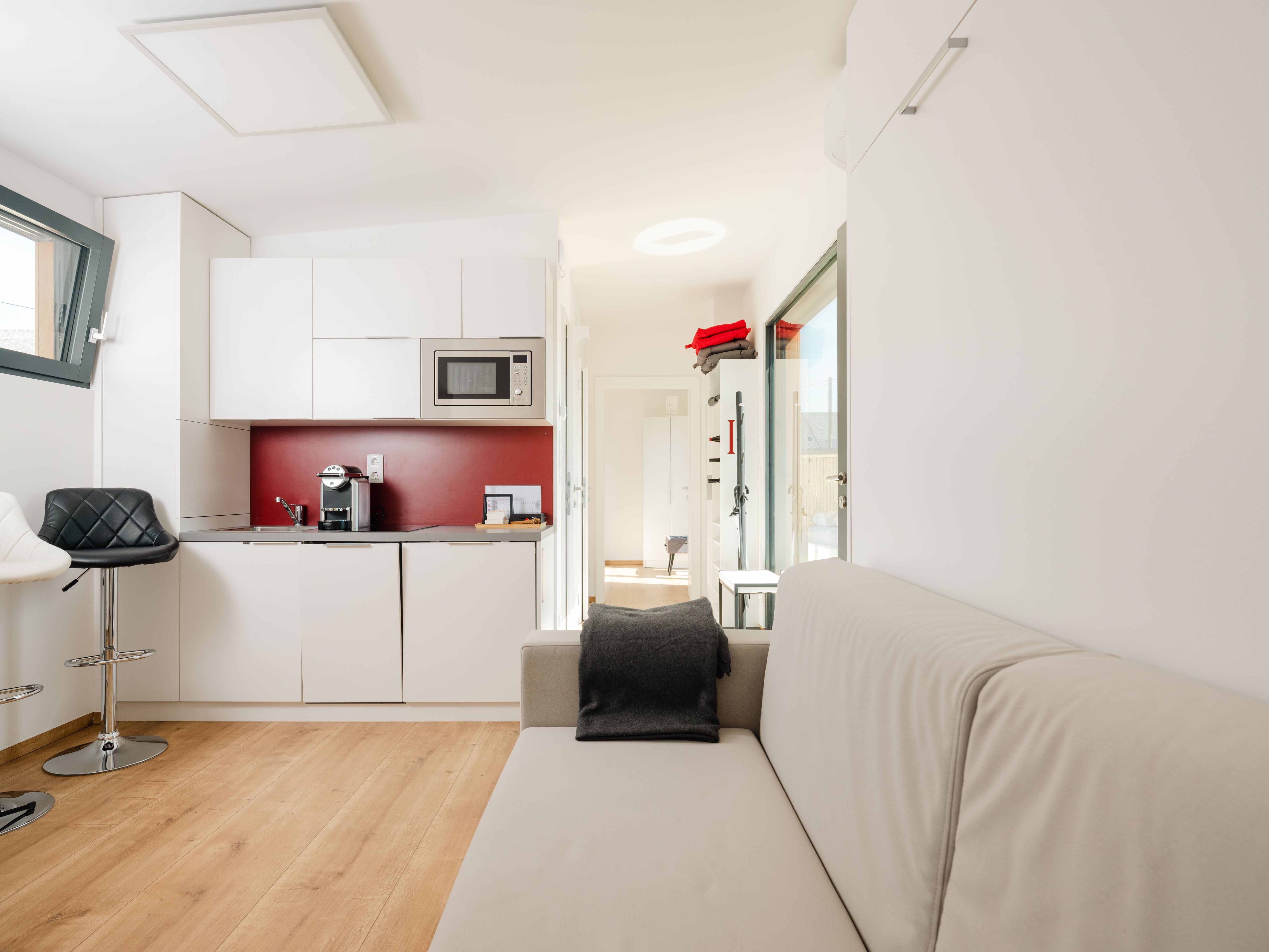 Modern apartment with kitchenette, sofa and bar stool.