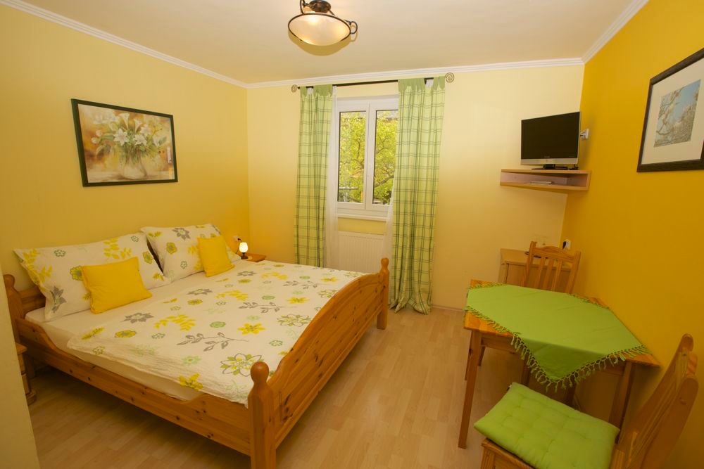 Cozy guest room with double bed, yellow walls and small table.
