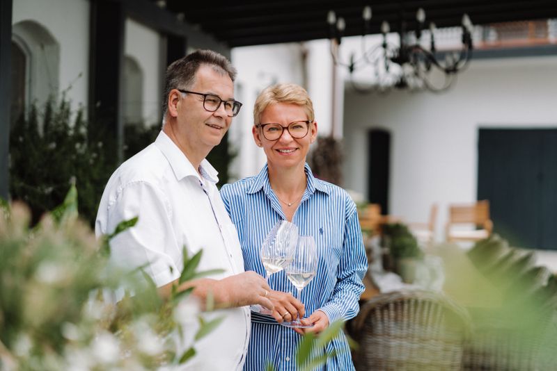 Two people are standing outside holding glasses of wine.