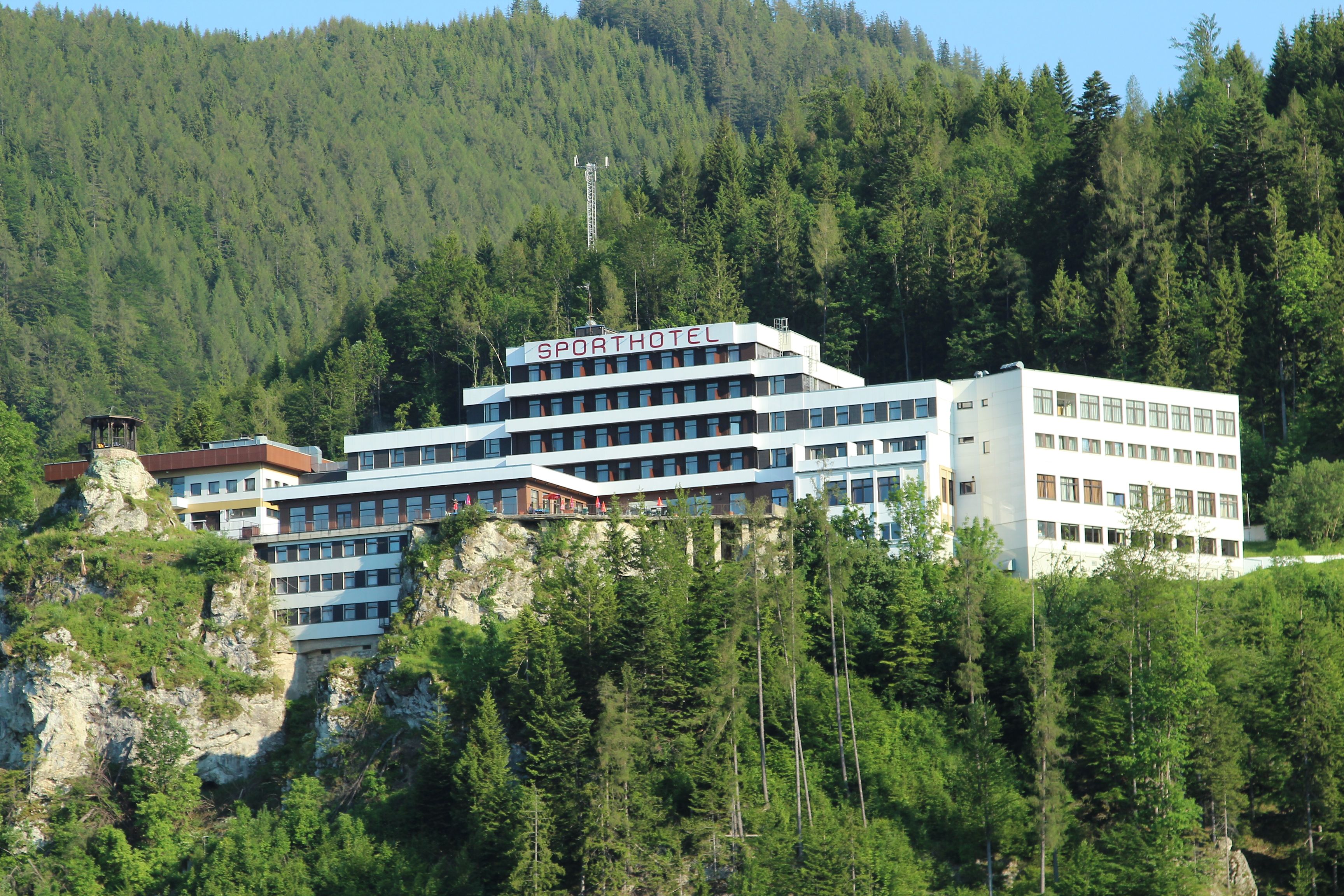 A large, modern hotel building on a wooded hill.