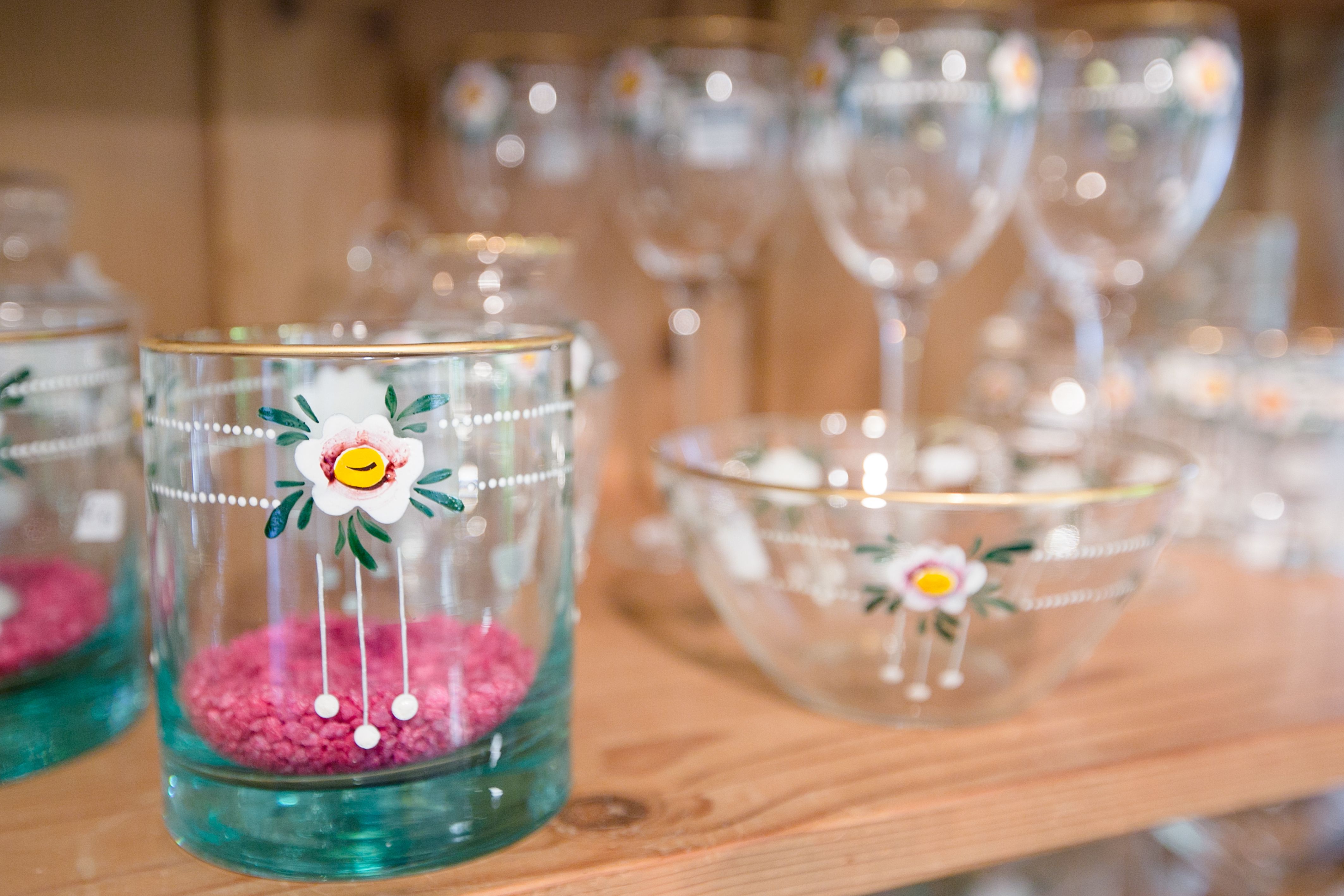 Glasses and bowls with floral motifs on a wooden shelf.