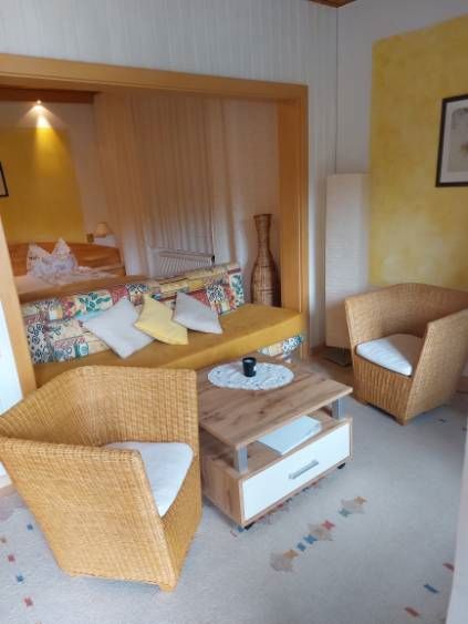 Cozy guest room with rattan furniture and colorful sofa.