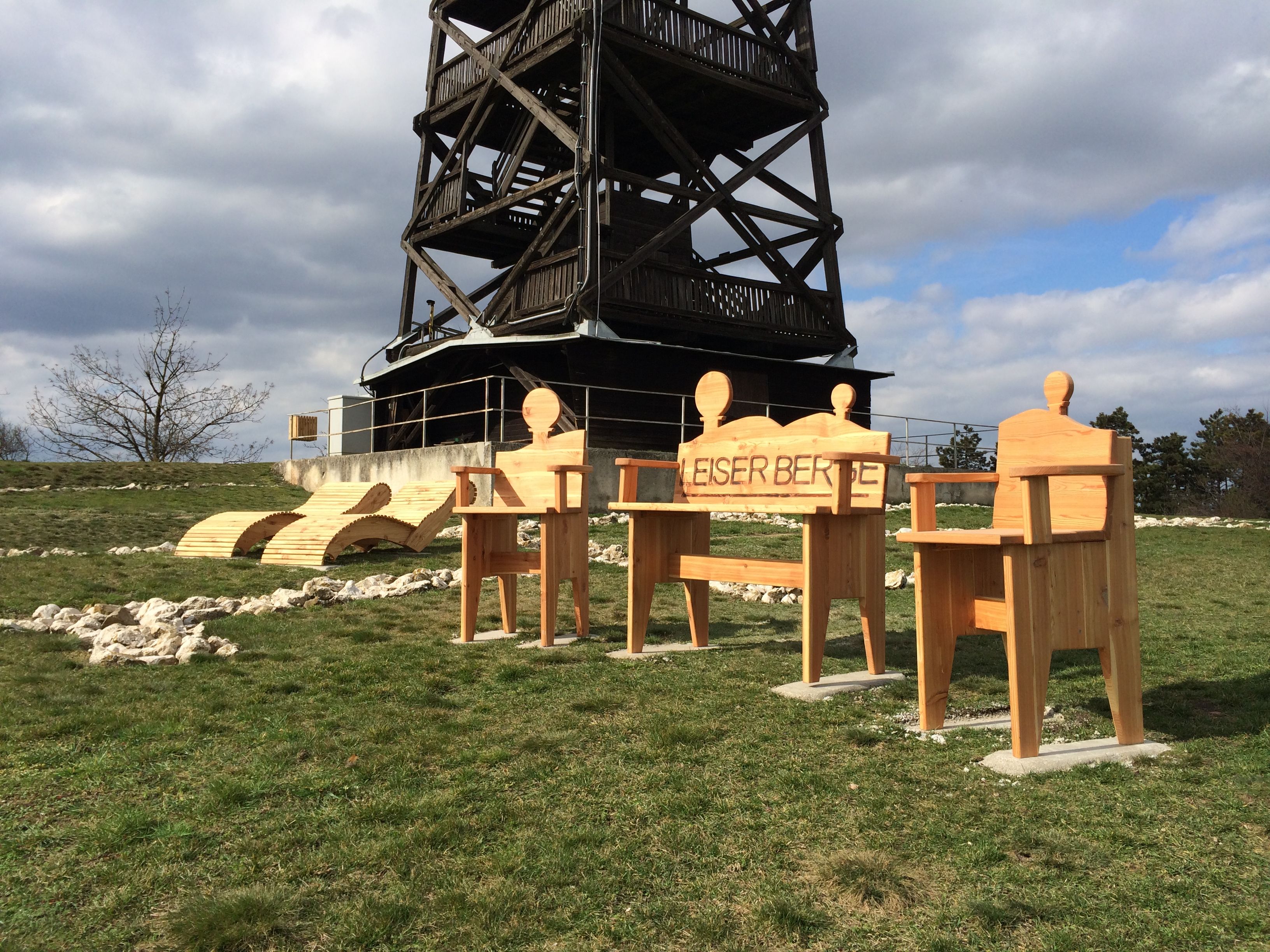 Wooden chairs and loungers in front of an outdoor viewing tower.