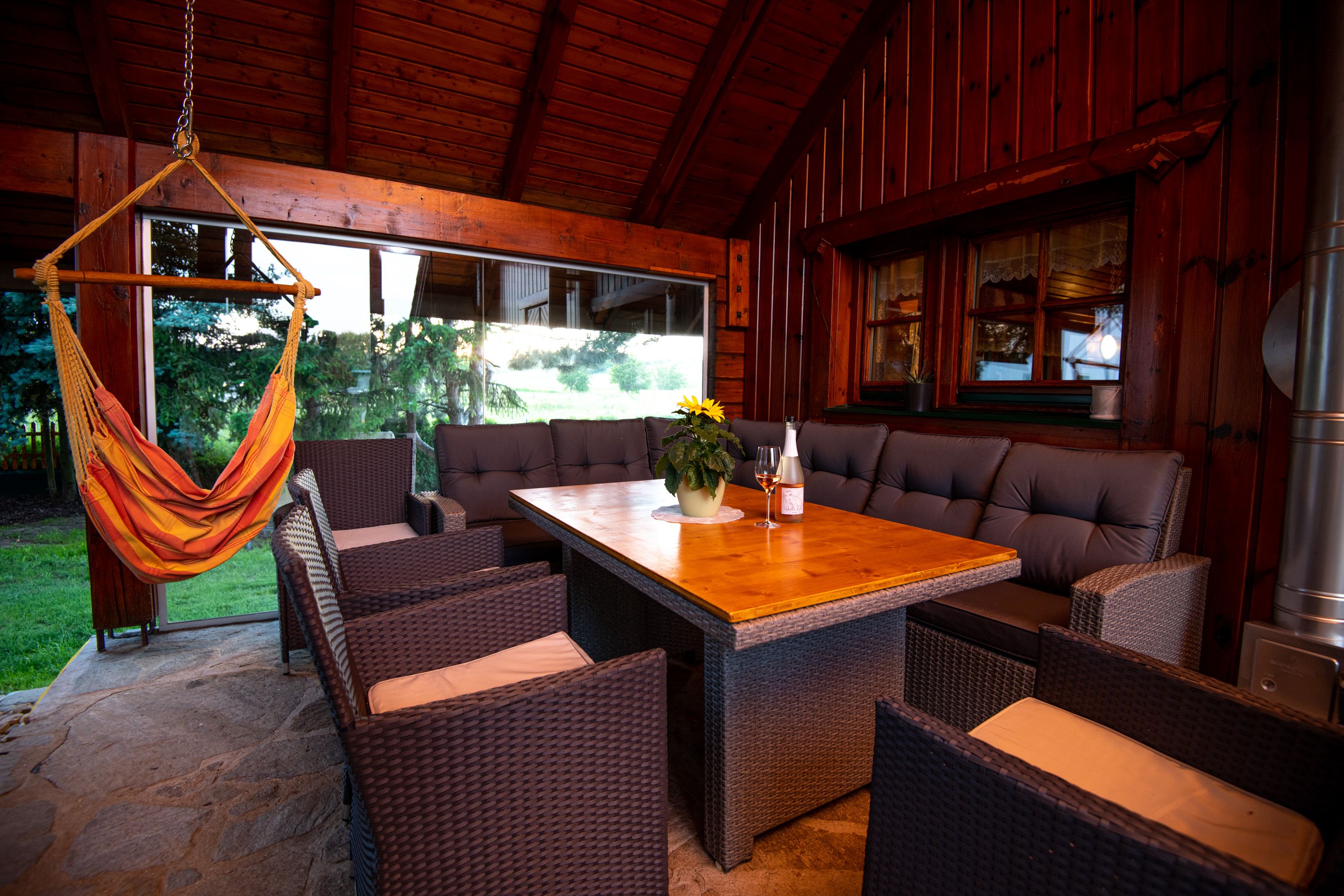 Covered terrace with wooden table, rattan furniture and hanging chair.