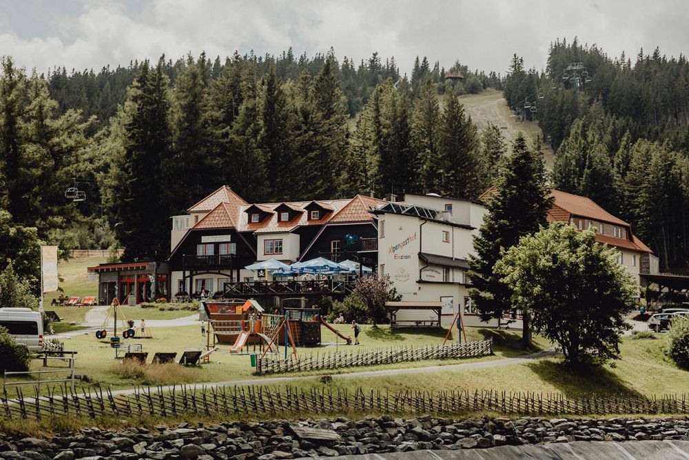 An inn in a mountainous landscape with a playground and forest in the background.