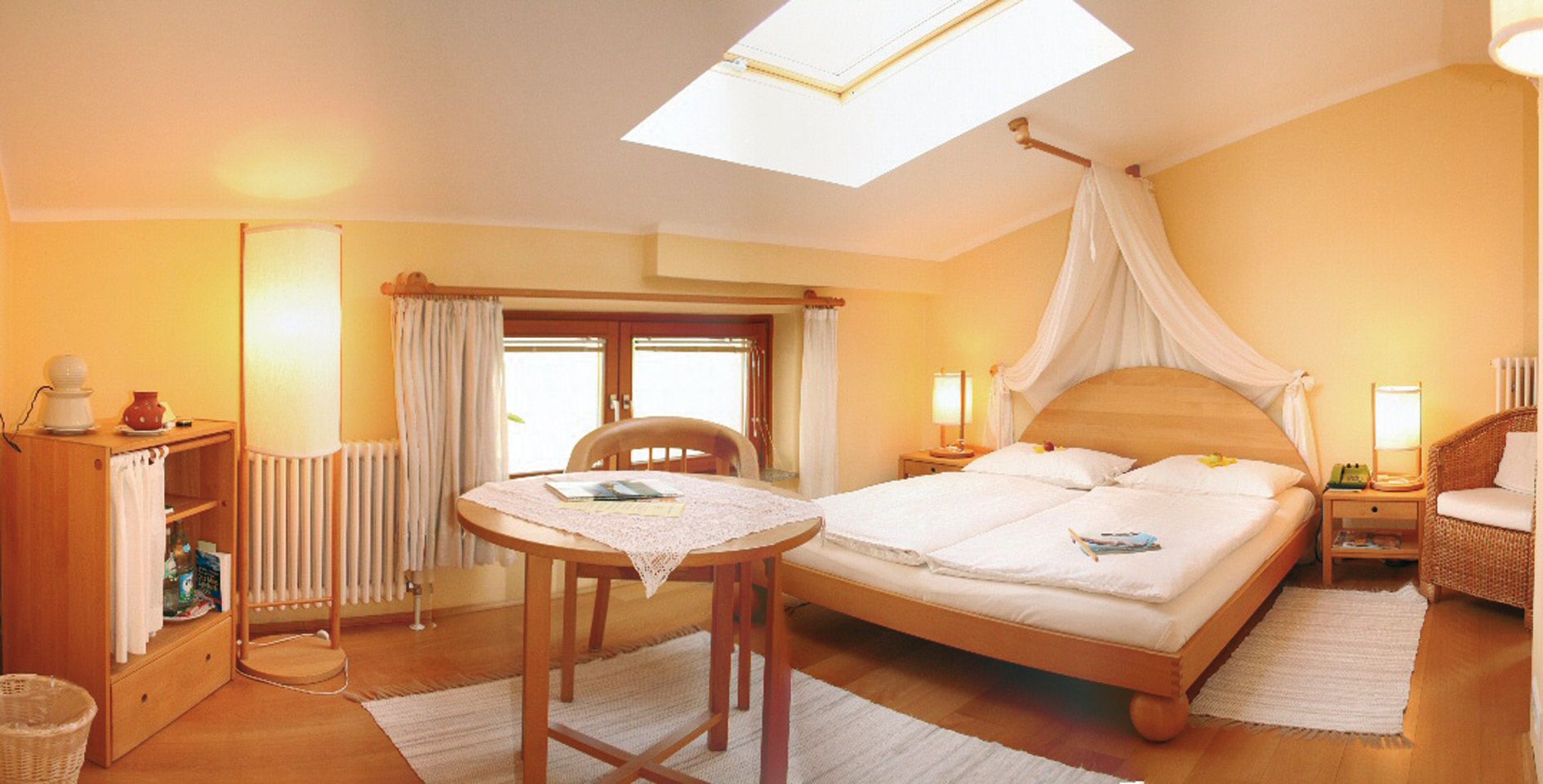 Comfortable hotel room with double bed, table and skylight.