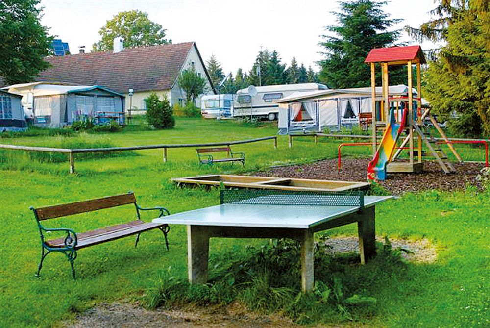 Campsite with table tennis table, playground and caravan.
