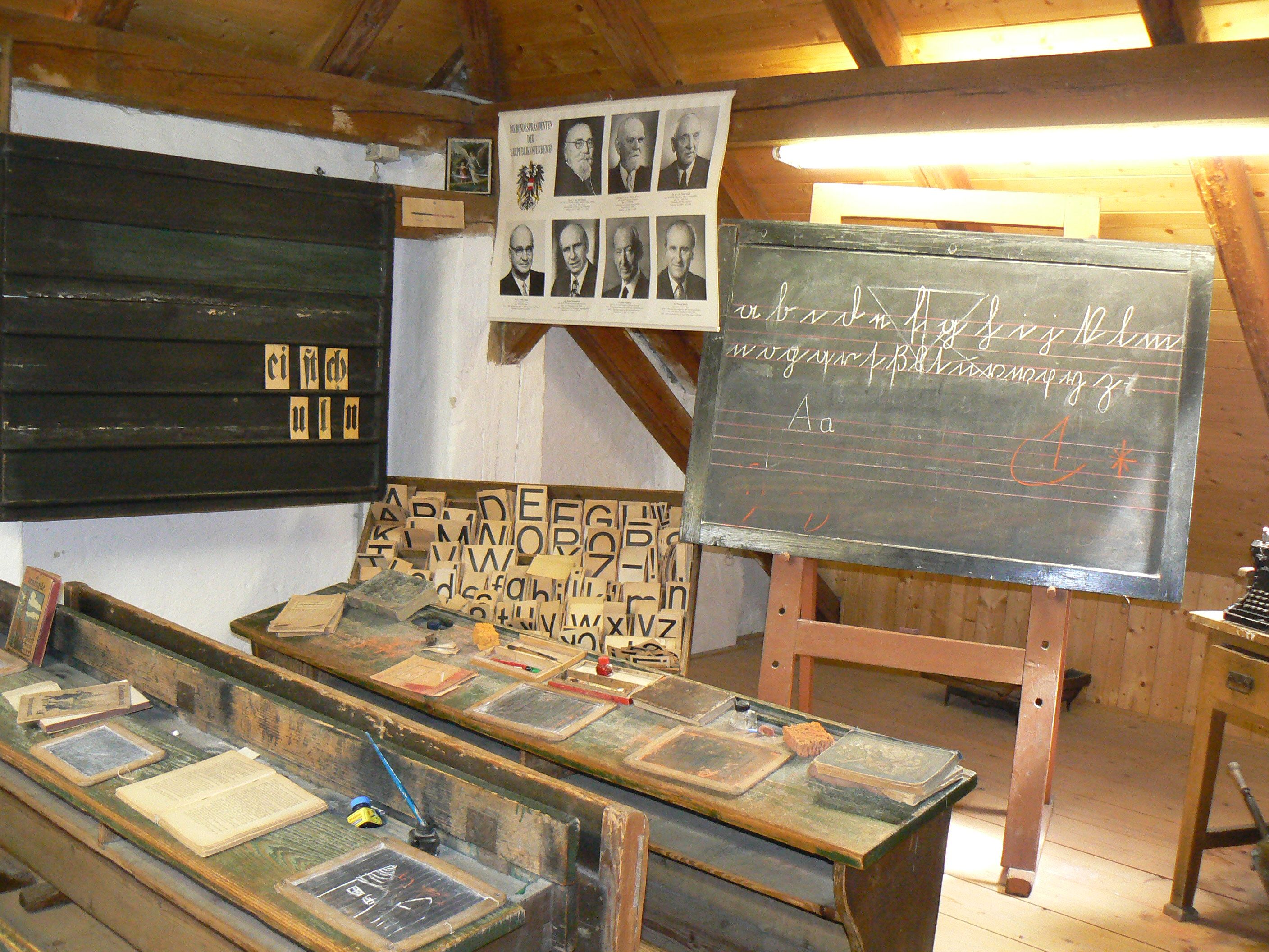 Historic classroom with blackboard, desk and teaching materials.