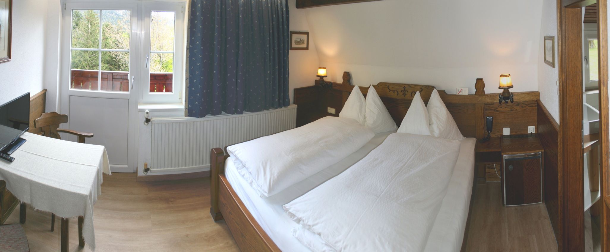 Cozy bedroom with double bed, wooden furniture and window with a view of the greenery.