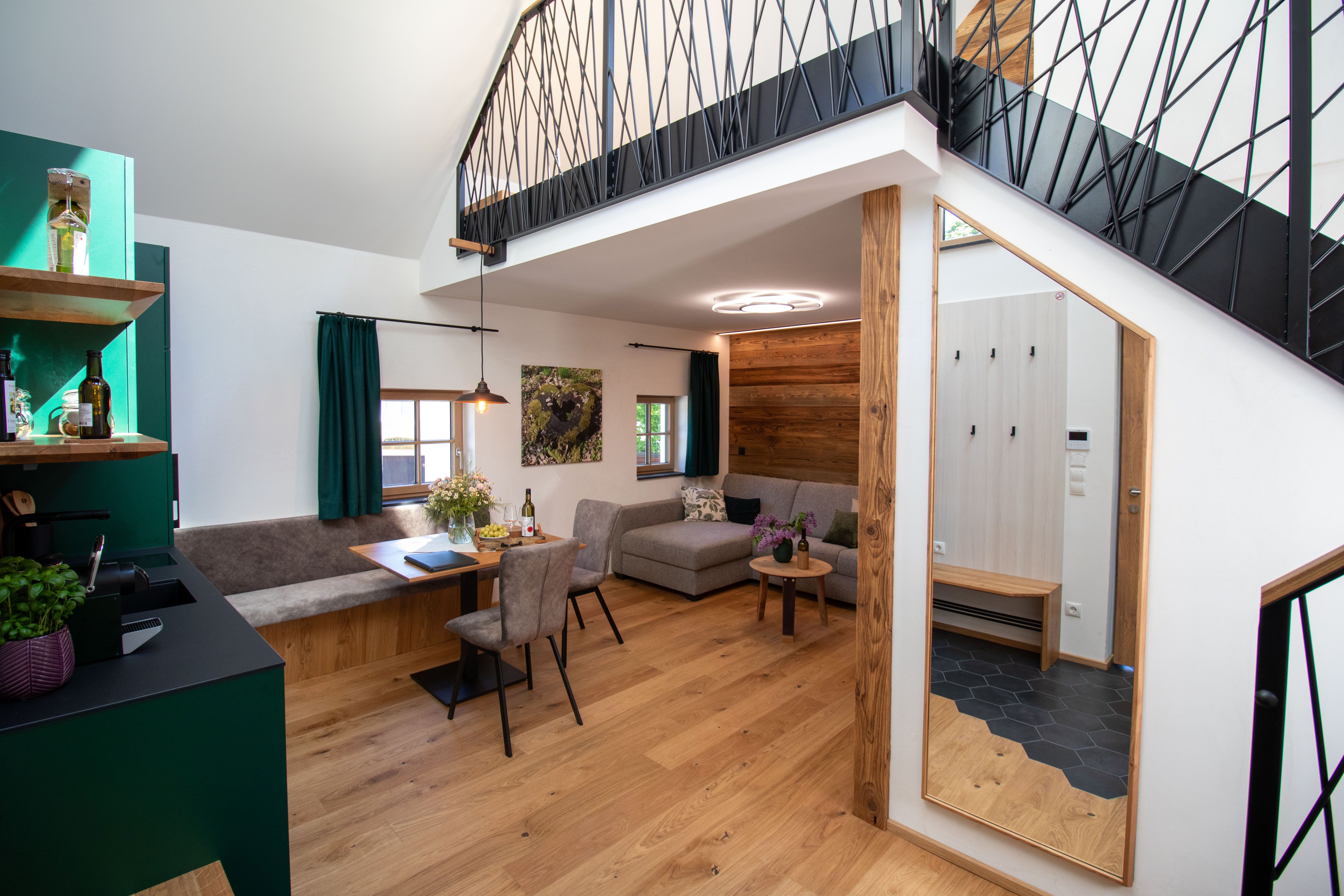 Modern apartment with wooden floor, gray sofa, dining table and open gallery.