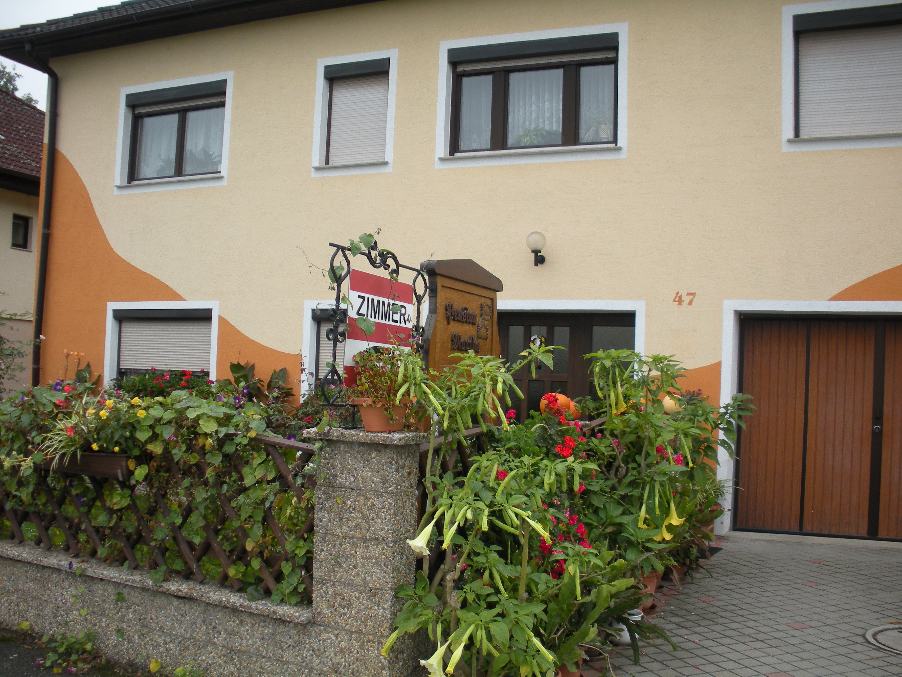 House with yellow façade, floral decoration and 'Room' sign.