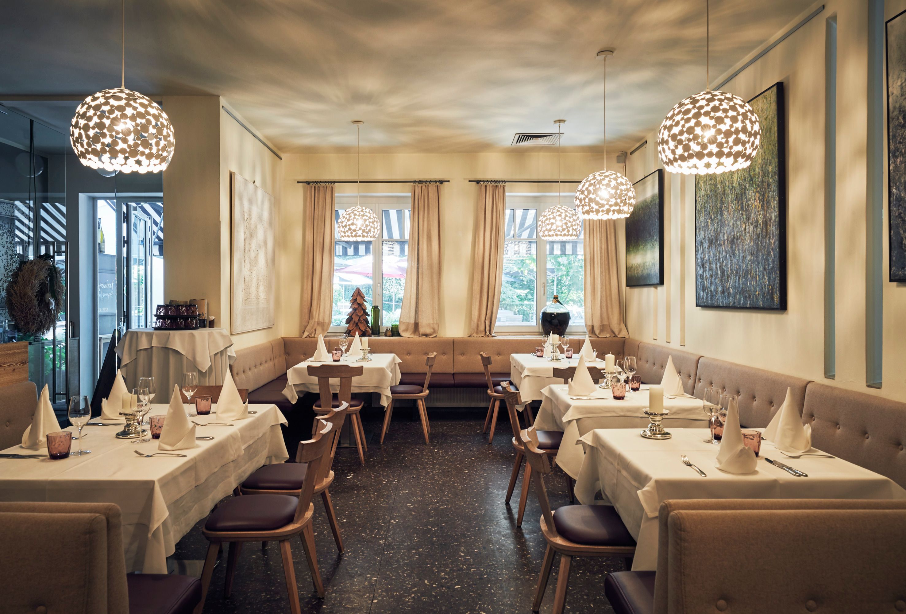 Elegant restaurant with laid tables, modern lamps and art on the walls.