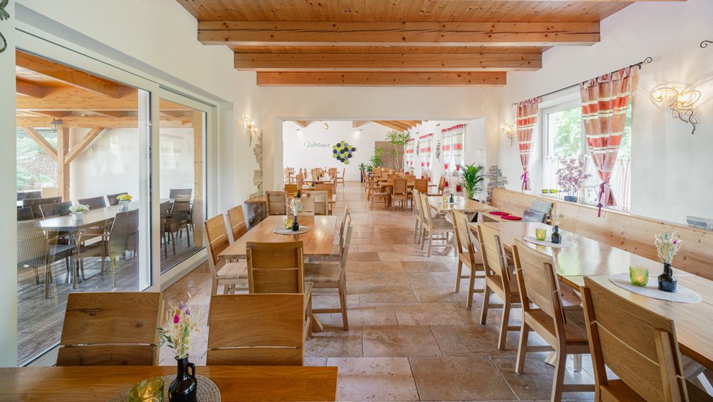 Interior view of a cozy wine tavern with wooden furniture and decorative curtains.