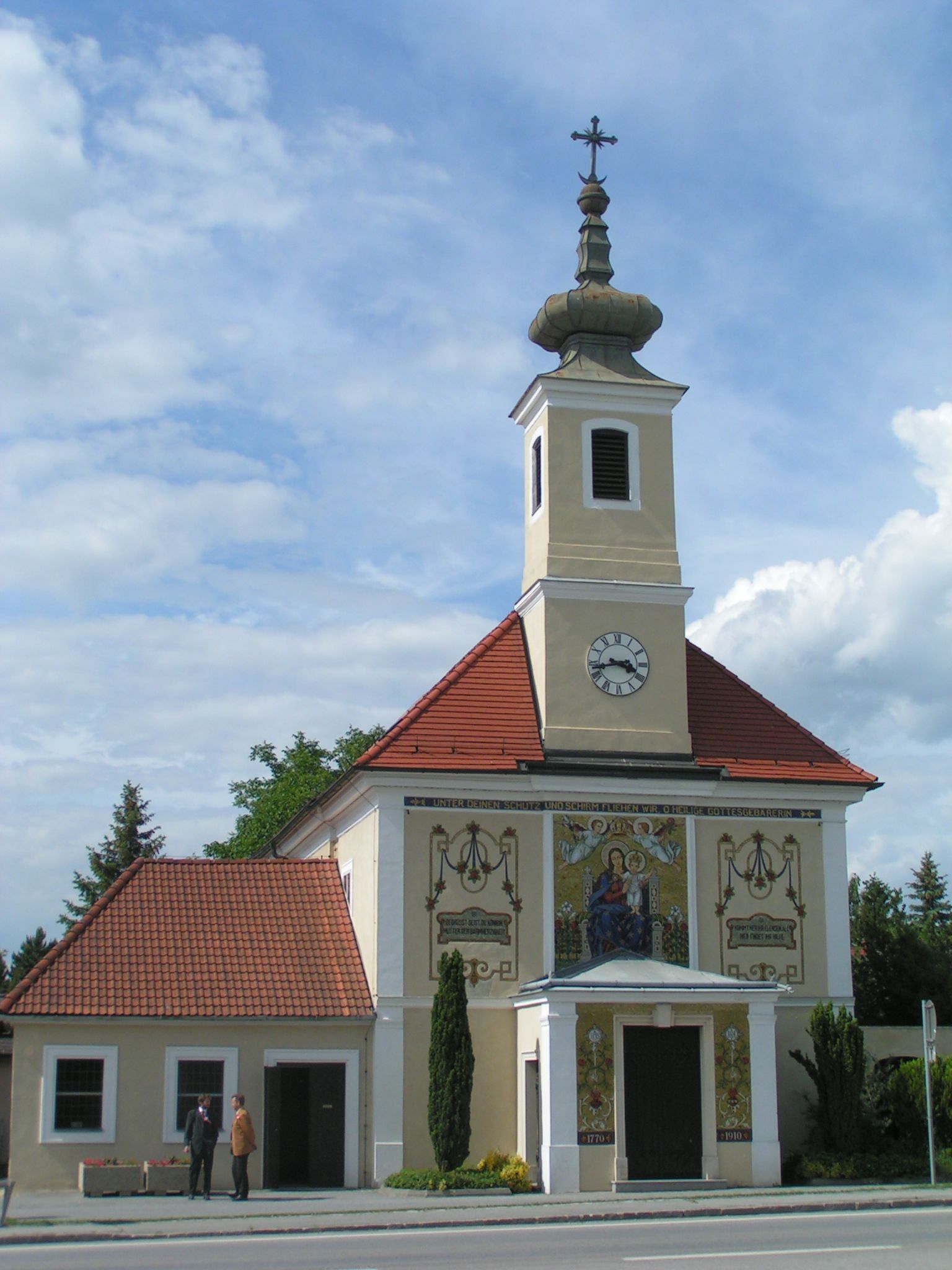 Maria Ellend pilgrimage church with tower and clock, decorated with religious motifs.