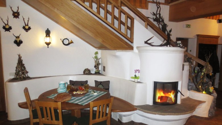 Cozy interior with fireplace, wooden table and staircase.