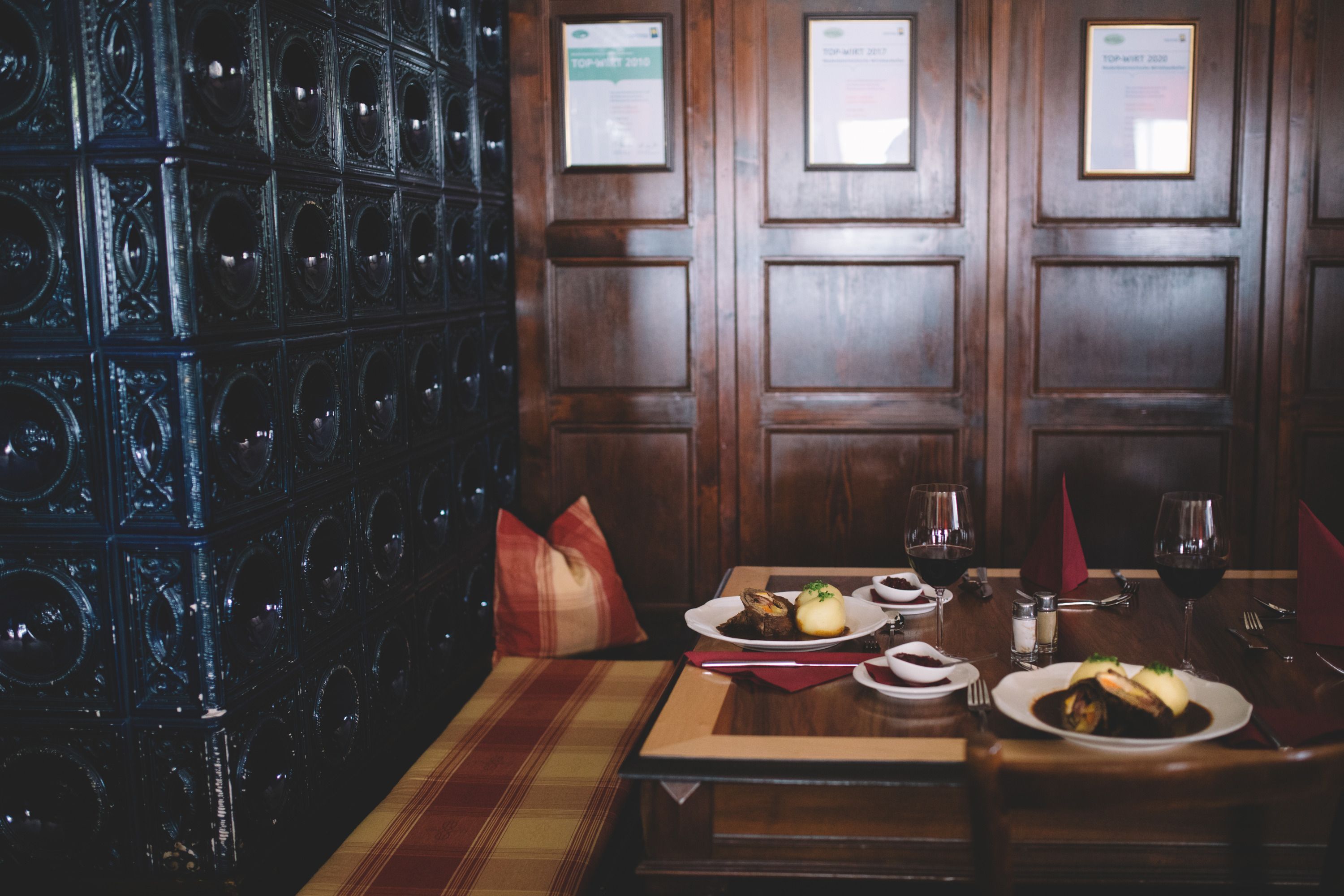 Cozy dining room with wooden walls, table setting and tiled stove.