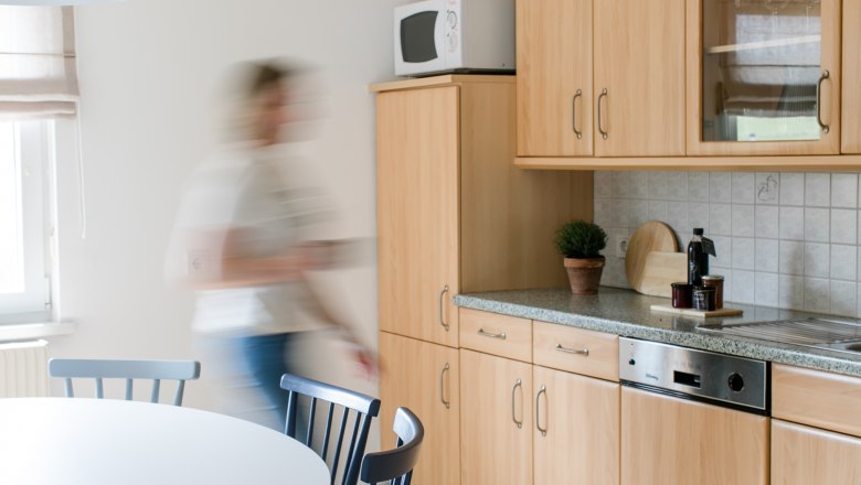 Modern kitchen with wooden furniture and one person on the move.