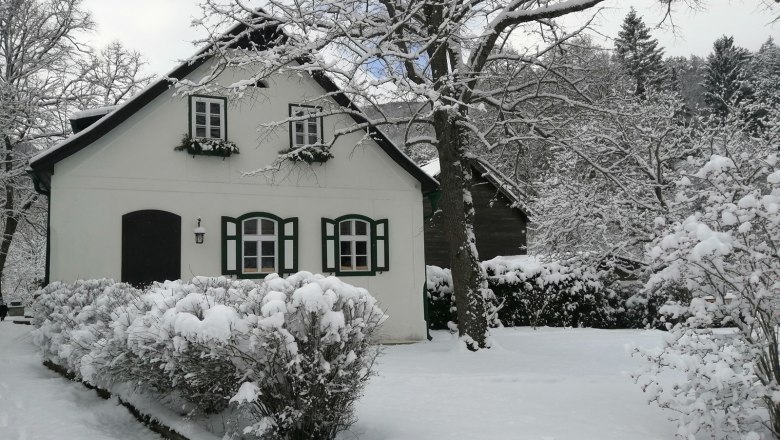 Country estate Oberhof, © Landsitz Oberhof Snow-covered house with green shutters and trees in the background.