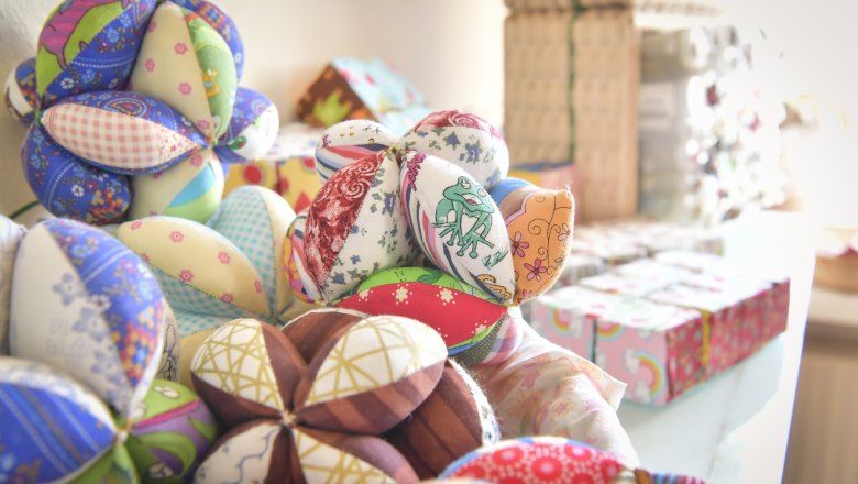 Colorful, handmade fabric balls in different patterns and colors on a table.