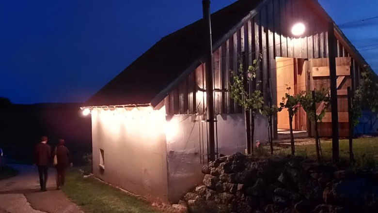 Illuminated wine cellar building at night with two people on a path.