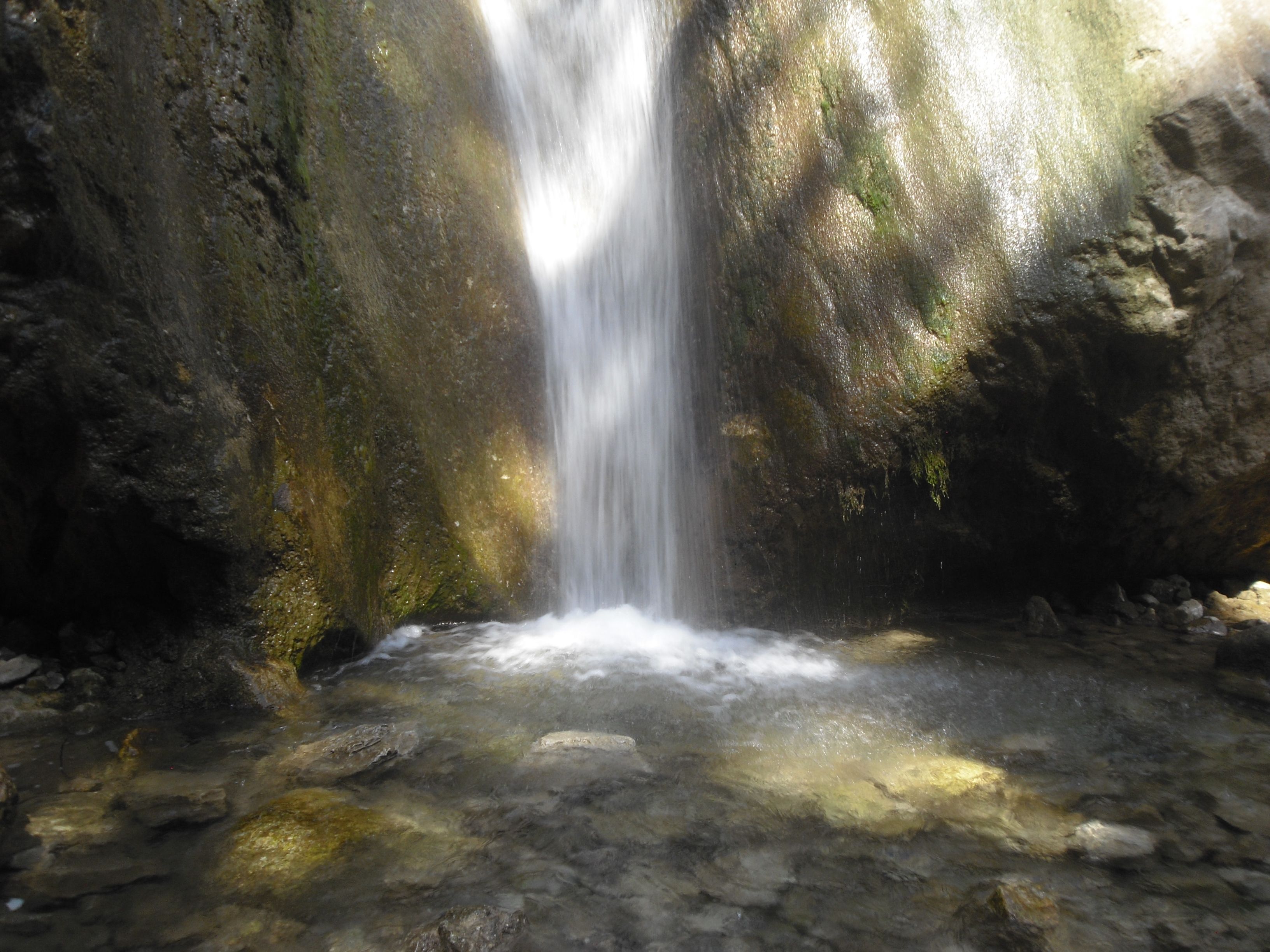 Waterfall in a rocky environment with a clear pool of water.