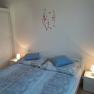 Cozy bedroom with double bed, blue bed linen, bedside tables with lamps and a wall tattoo with flowers and birds.