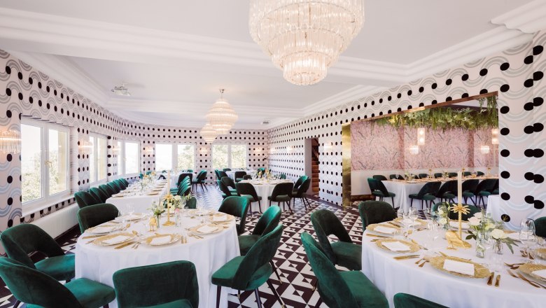 Restaurant, © Matthias Kronfuss Elegant restaurant with round tables, green chairs and chandeliers.