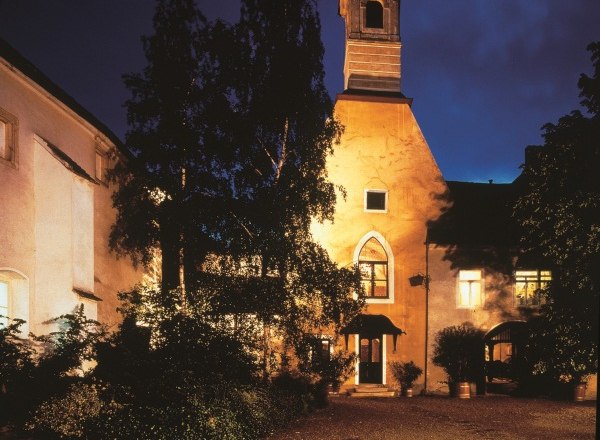 Illuminated building at night with tower and trees in the foreground.