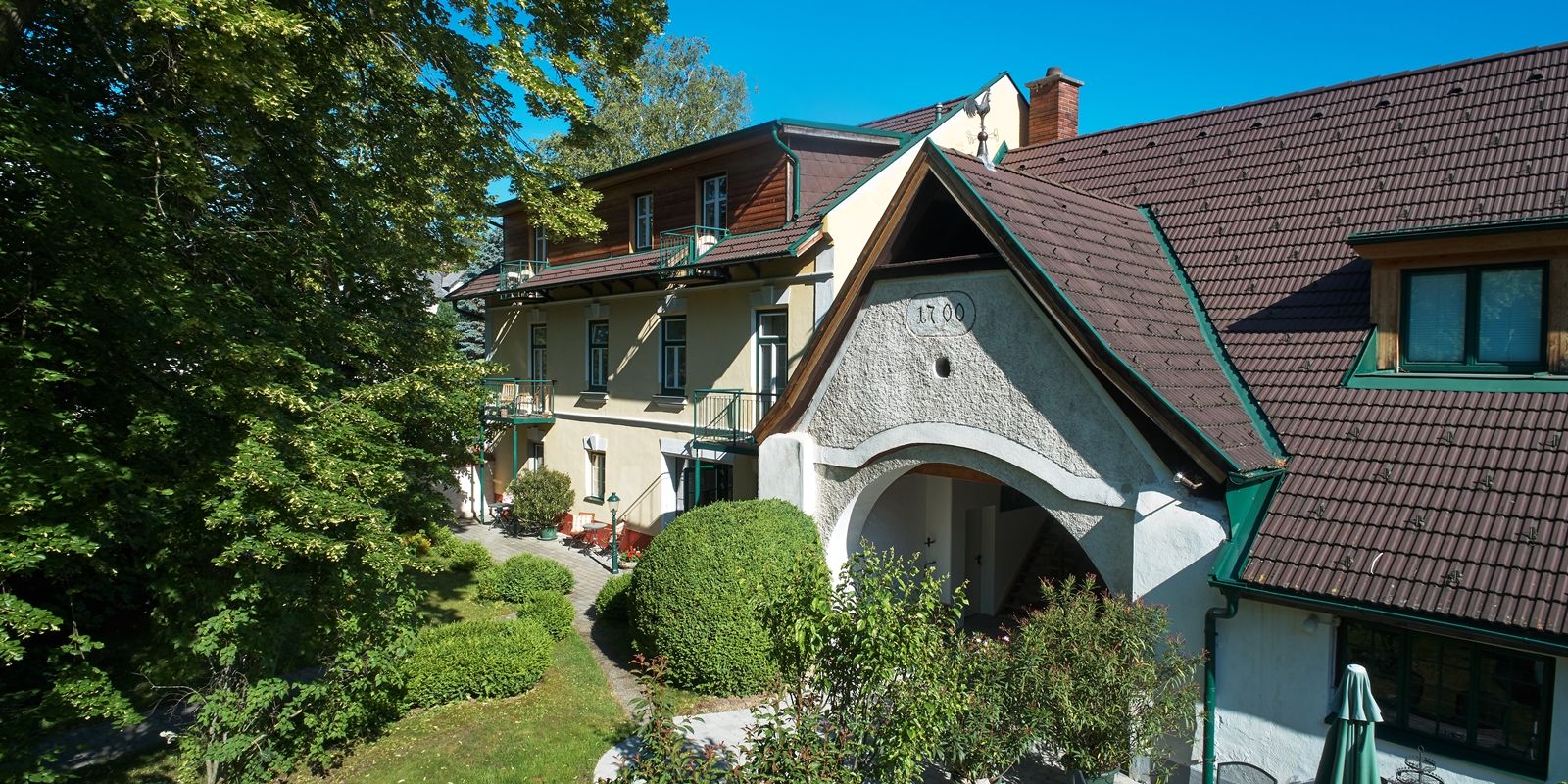 Landhaus Puchbergerhof with garden and trees in the foreground.