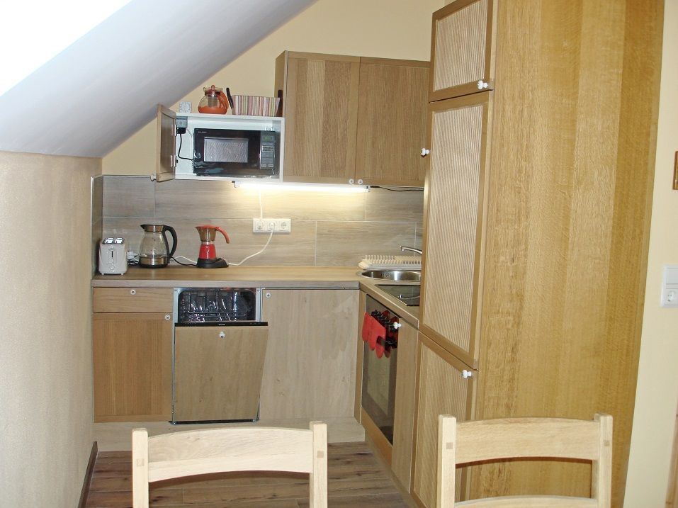 Small kitchen in a vacation apartment with wooden cupboards, microwave, coffee machine and sink.