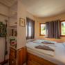 Interior view of a cozy bedroom with double bed, shelves and windows with curtains.