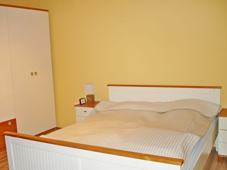 Bedroom with double bed, yellow wall and white closet.