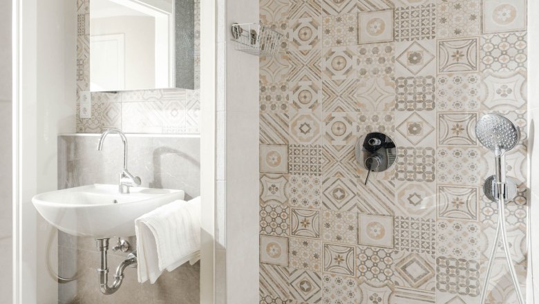 Modern bathroom with patterned tiles, washbasin and rain shower.