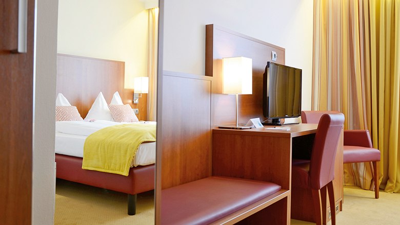 Double room in the Wachauerhof with bed, desk, TV and chair.