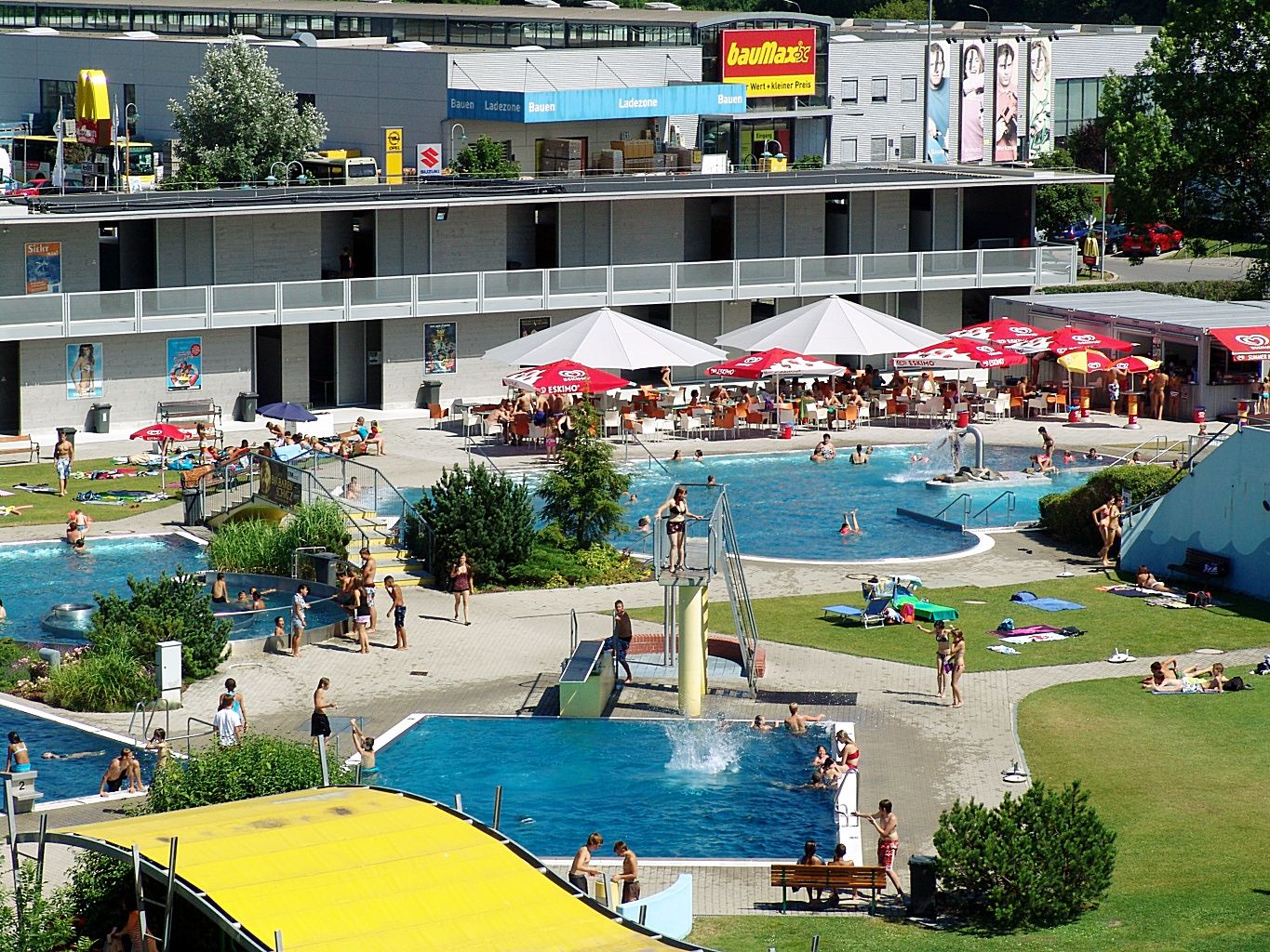 Outdoor area of a swimming pool with several pools and sunbathing lawn.