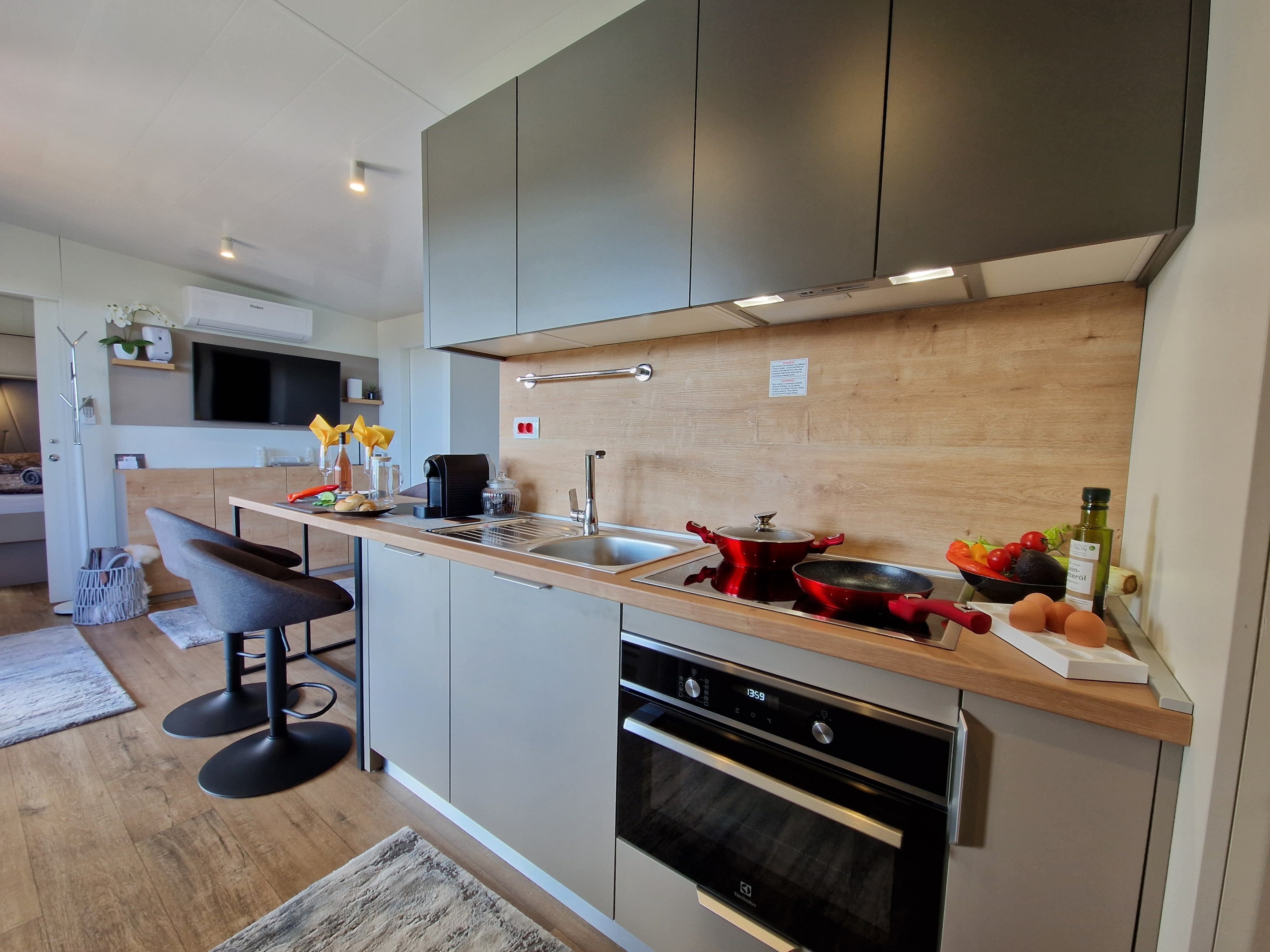 Modern kitchen with gray cabinets, stove, sink and bar stools.