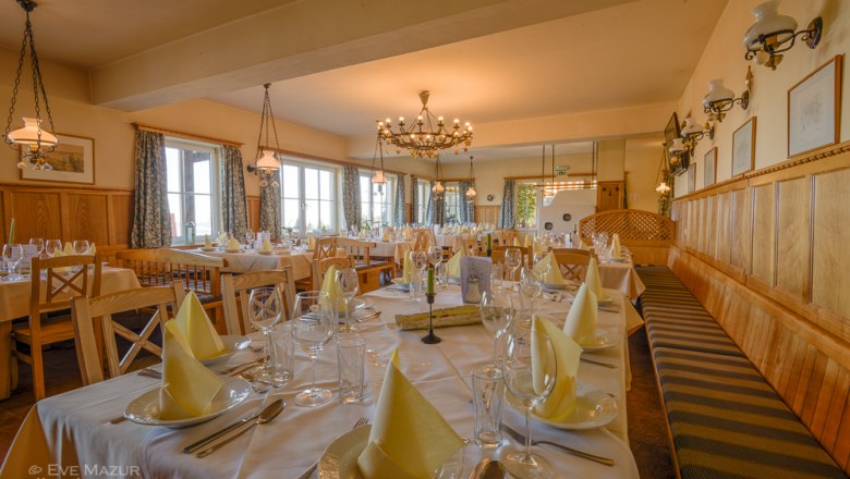 Elegant restaurant with laid tables and chandeliers.