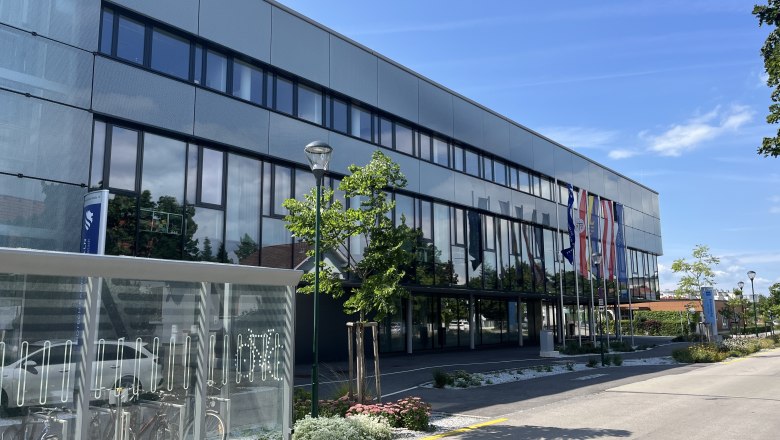 Modern building with glass fa&ccedil;ade and e-bike charging station in the foreground.